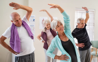 Group of seniors doing stretching exercise together at retirement community.